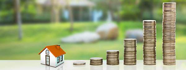 Tiny house model next to stacked coins